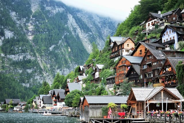 Wooden houses of Hallstatt on the lakeshore below steep mountains