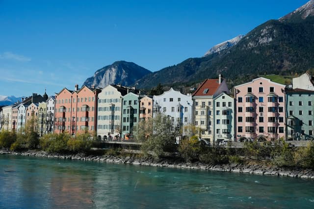 Colourful houses along the Inn river with mountains behind