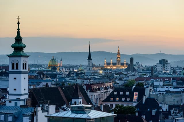 Vienna rooftops at dusk with the City Hall and church spires