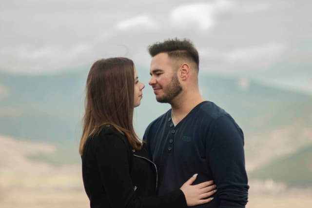 Couple standing close together with hazy hills behind them