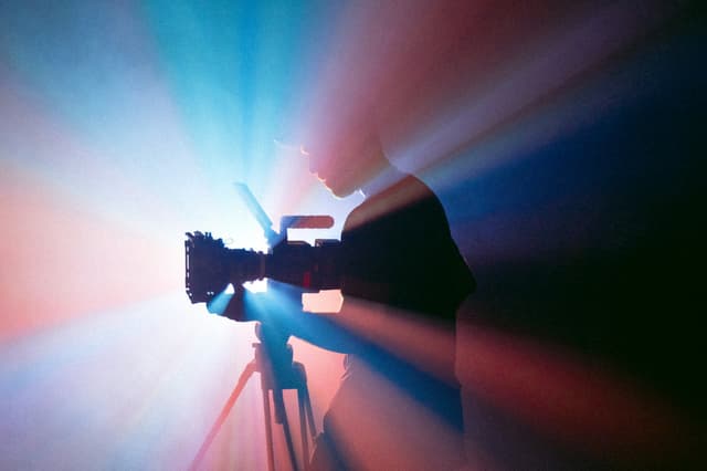 Camera operator silhouetted against stage lights