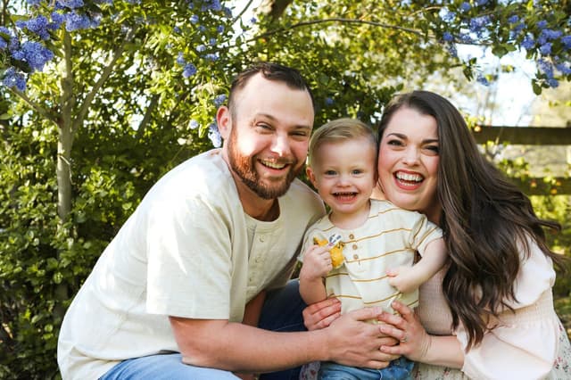 Laughing parents with their toddler in a garden