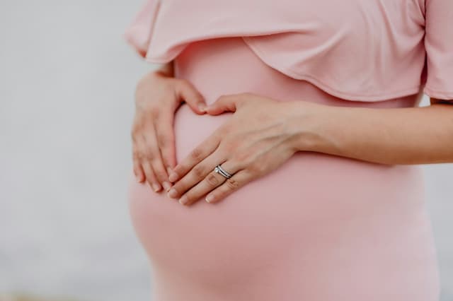 Pregnant woman holding her belly in soft light